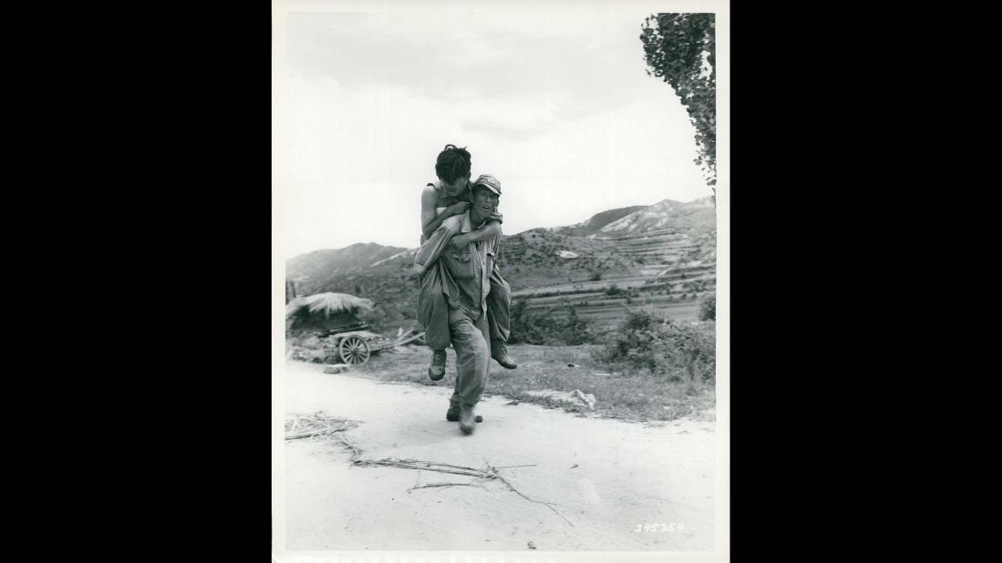 A South Korean soldier carries a wounded comrade in an unknown location in Korea in July 1950. Photo ID: SC 345354