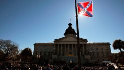 COLUMBIA, SC - JANUARY 21:  A Confederate flag that's part of a Civil War memorial on the grounds of the South Carolina State House flies over a Martin Luther King  Day rally January 21, 2008 in Columbia, South Carolina.  All three major Democratic candidates for President spoke to a large crowd on the state house grounds.  (Photo by Chris Hondros/Getty Images)
