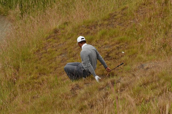 Down and out: Woods slips as he negotiates the rough on the 10th hole on his way to missing the halfway cut at the U.S. Open in June.