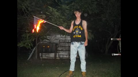 Photos taken May 11 show Roof burning and spitting on an American flag. Another May 11 photo shows him holding a small Confederate flag.