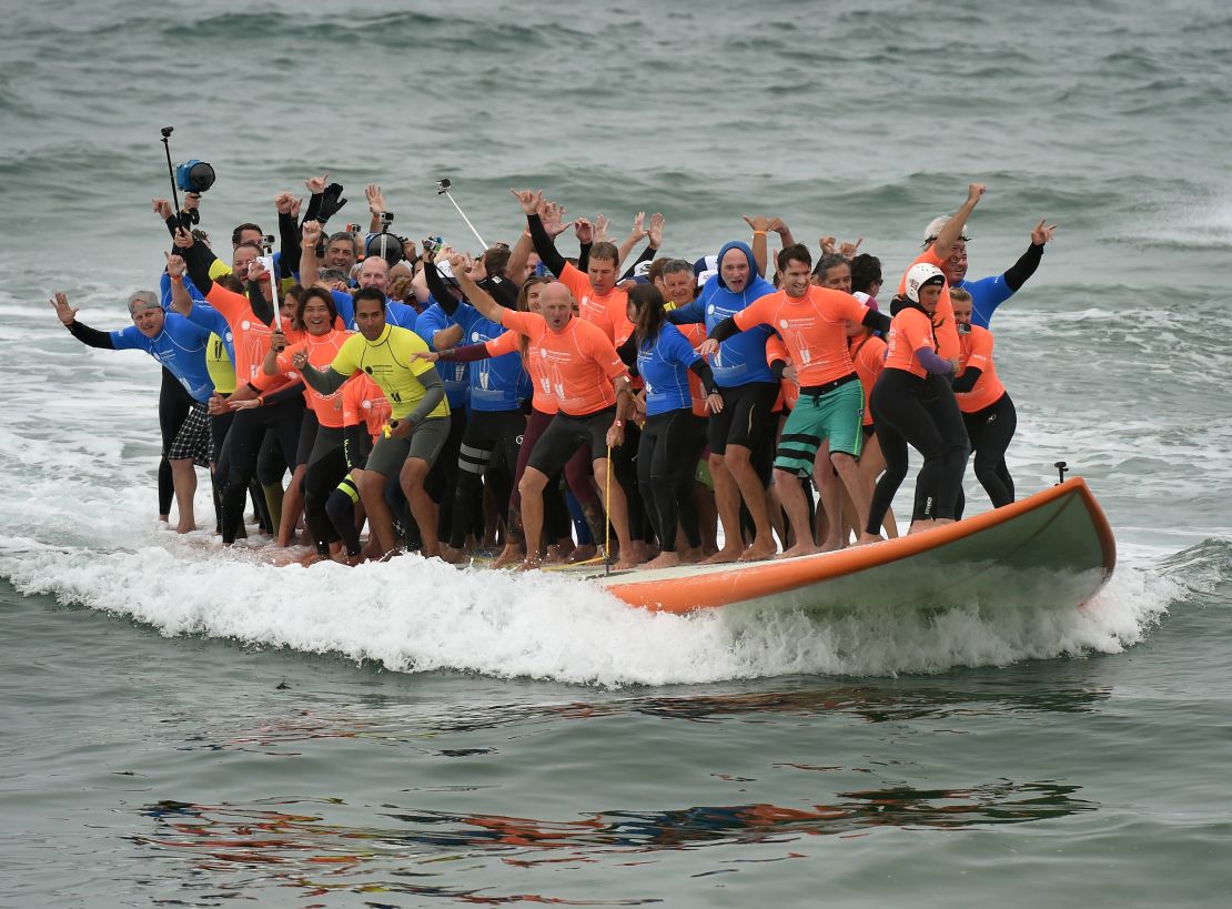 Sixty-six surfers ride a giant surfboard to set a world record Saturday in Huntington Beach, California. 