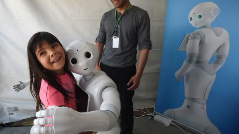 'Pepper,' a robot with emotional capabilities hugs a girl at DARPA Robotics Challenge on June 5, 2015.