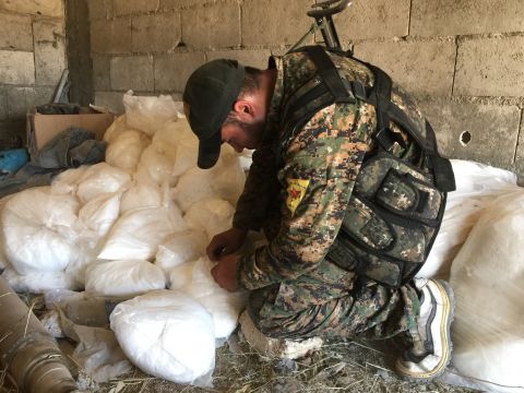 A YPG soldier looks through bags of sticky white powder, a low grade explosive that can be used to make car bombs.