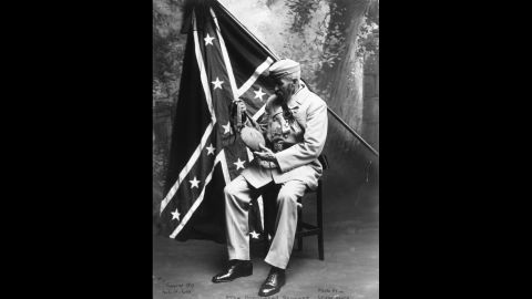 A veteran of the Confederate States of America examines a Union water bottle in front of a Confederate flag. Here's a look at the evolution of that flag.