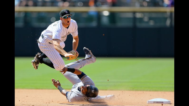 Second baseman D.J. LeMahieu of the Colorado Rockies is upended by Milwaukee Brewers' Martin Maldonado after throwing to first base to complete a double play at Coors Field on Saturday, June 20, in Denver. The Rockies defeated the Brewers 5-1. 