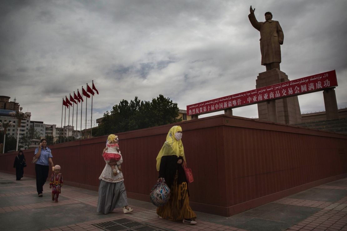  A veiled Muslim Uyghur woman walks passed a statue of Mao Zedong on July 31, 2014 in Kashgar, Xinjiang.