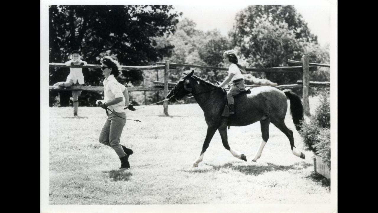 Jackie leading Caroline on a pony.