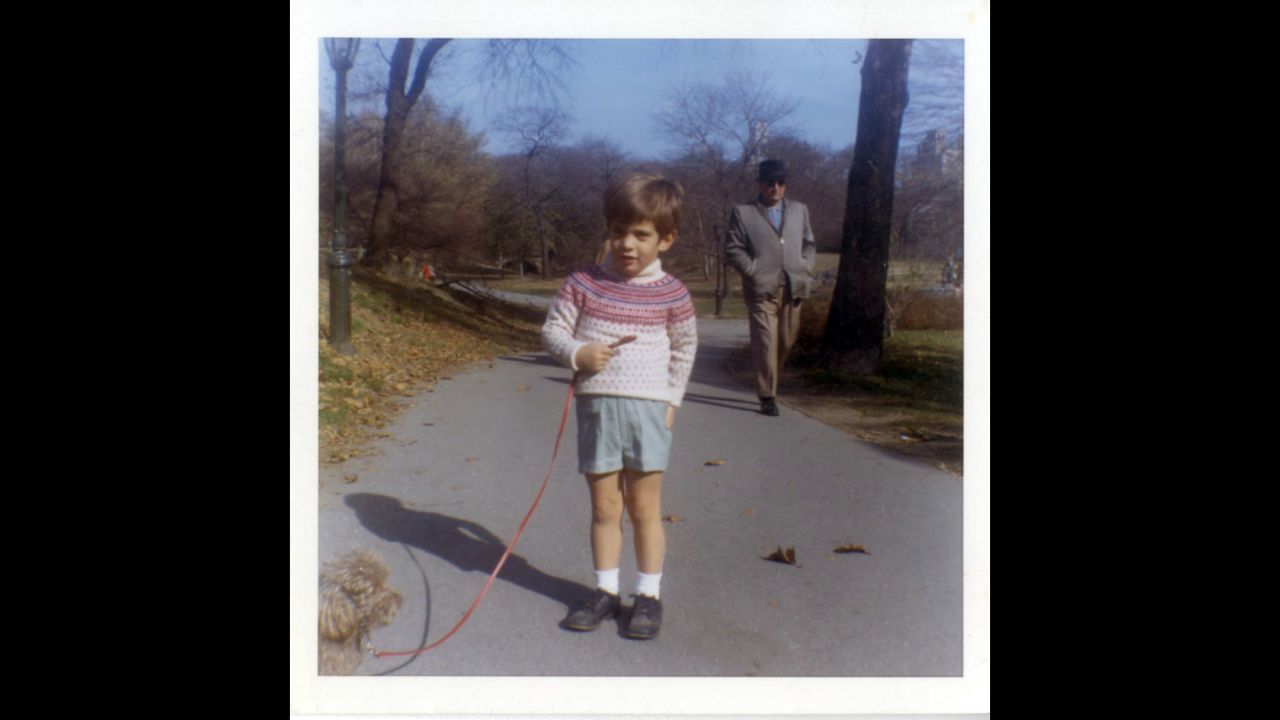 John F. Kennedy Jr. walking a dog in the park in December 1964.