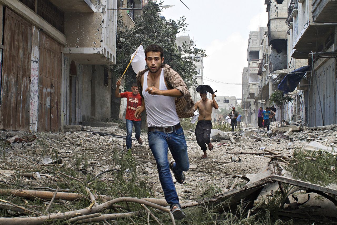 Palestinians run with a white flag in Gaza.<br /><br />"As the one year anniversary of the war approaches, I think both sides are basically holding their breath to see whether or not the ceasefire can stay in place."