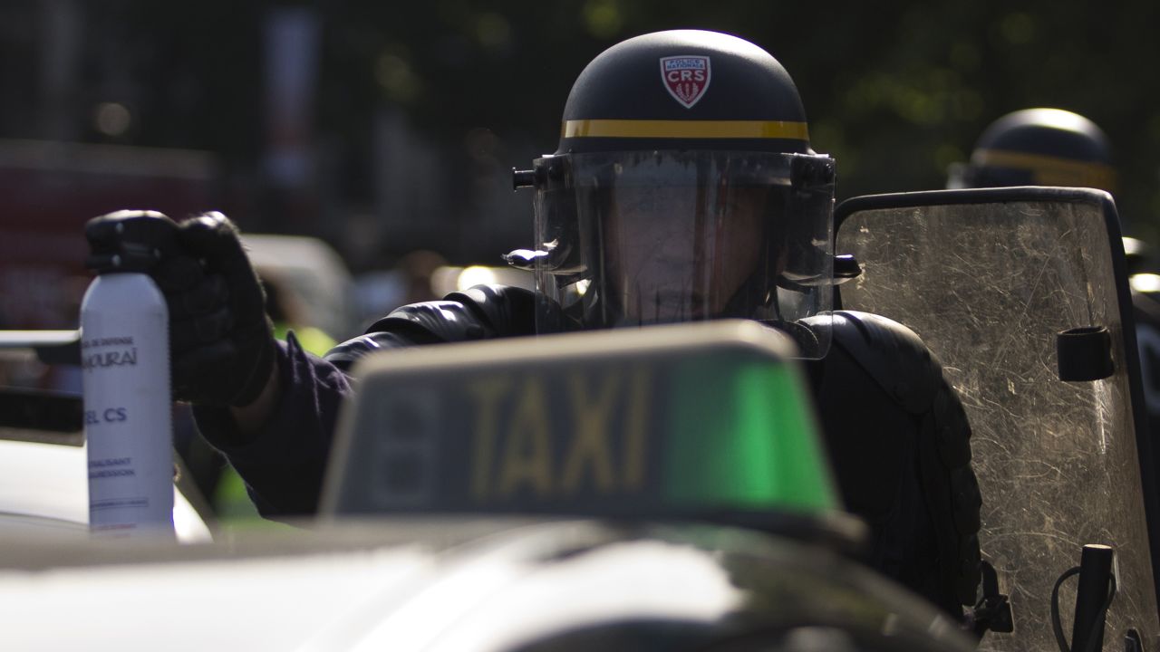 A police officer holds up a can of tear gas as taxi drivers block the Porte Maillot Métro station in Paris on June 25.