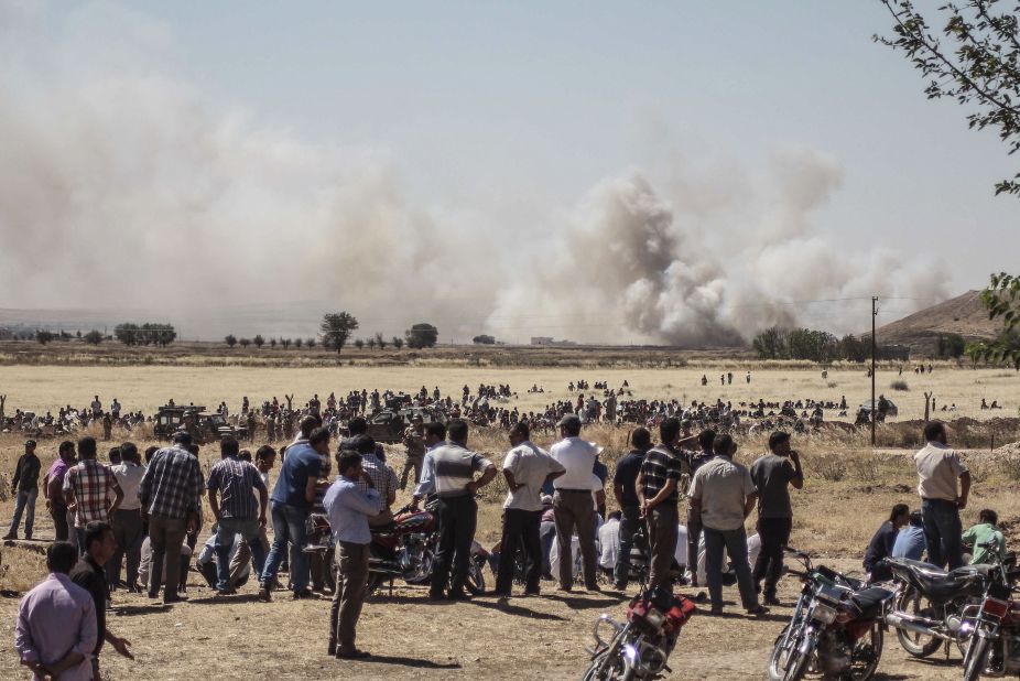 Syrians wait near the Turkish border during clashes between ISIS and Kurdish armed groups in Kobani, Syria, on Thursday, June 25. The photo was taken in Sanliurfa, Turkey. ISIS militants disguised as Kurdish security forces infiltrated Kobani on Thursday and killed "many civilians," said a spokesman for the Kurds in Kobani.