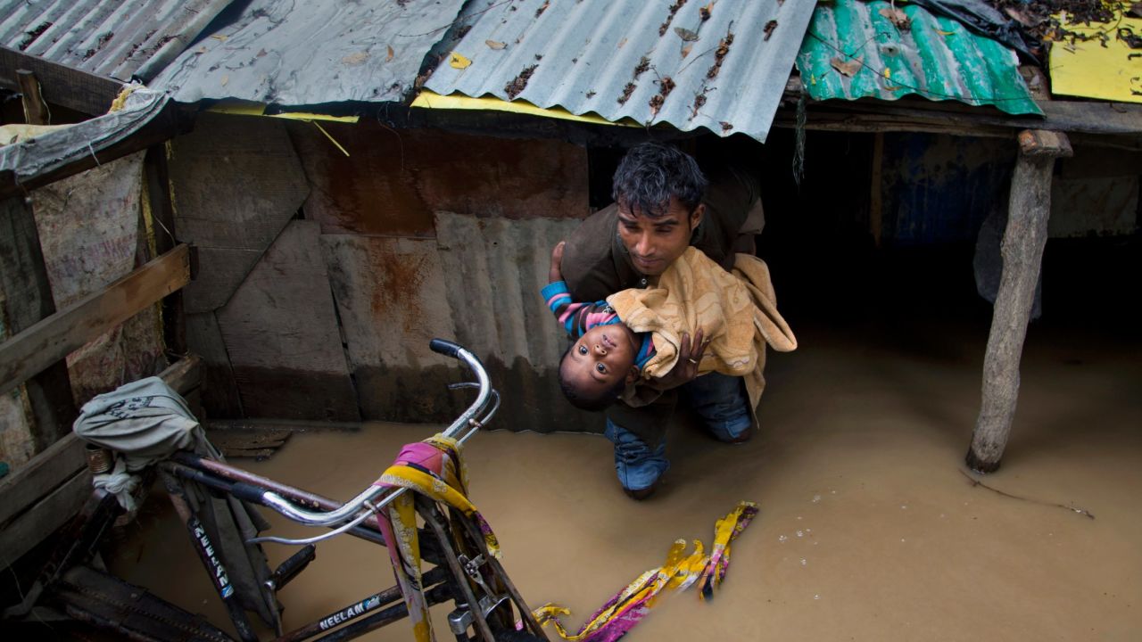 A man carries a boy to a safer place after their neighborhood was flooded in Srinagar, India, on Thursday, June 25.