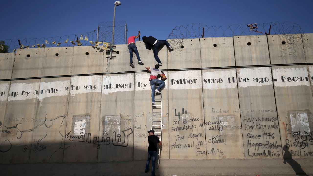 Young Palestinians from the West Bank climb over an Israeli barrier Friday, June 19, as they try to make their way to Jerusalem's Al-Aqsa Mosque to attend the first Friday prayer of Ramadan.