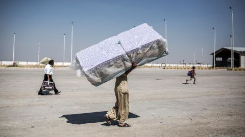 A refugee carries mattresses as he re-enters Syria from Turkey on June 22, 2015, after Kurdish People's Protection Units regained control of the area around Tal Abyad, Syria, from ISIS.