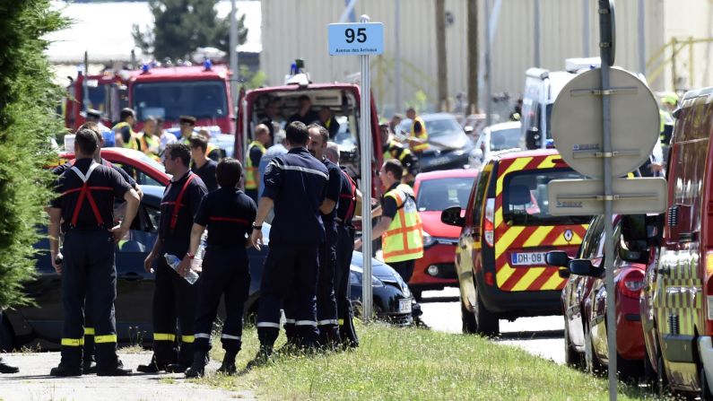 Police and firefighters gather at the entrance of Air Products & Chemicals, a gas factory near Lyon, France, on Friday, June 26, after a terror attack. One person has been beheaded and two people injured, French President François Hollande said Friday. A suspect has been arrested, he said.
