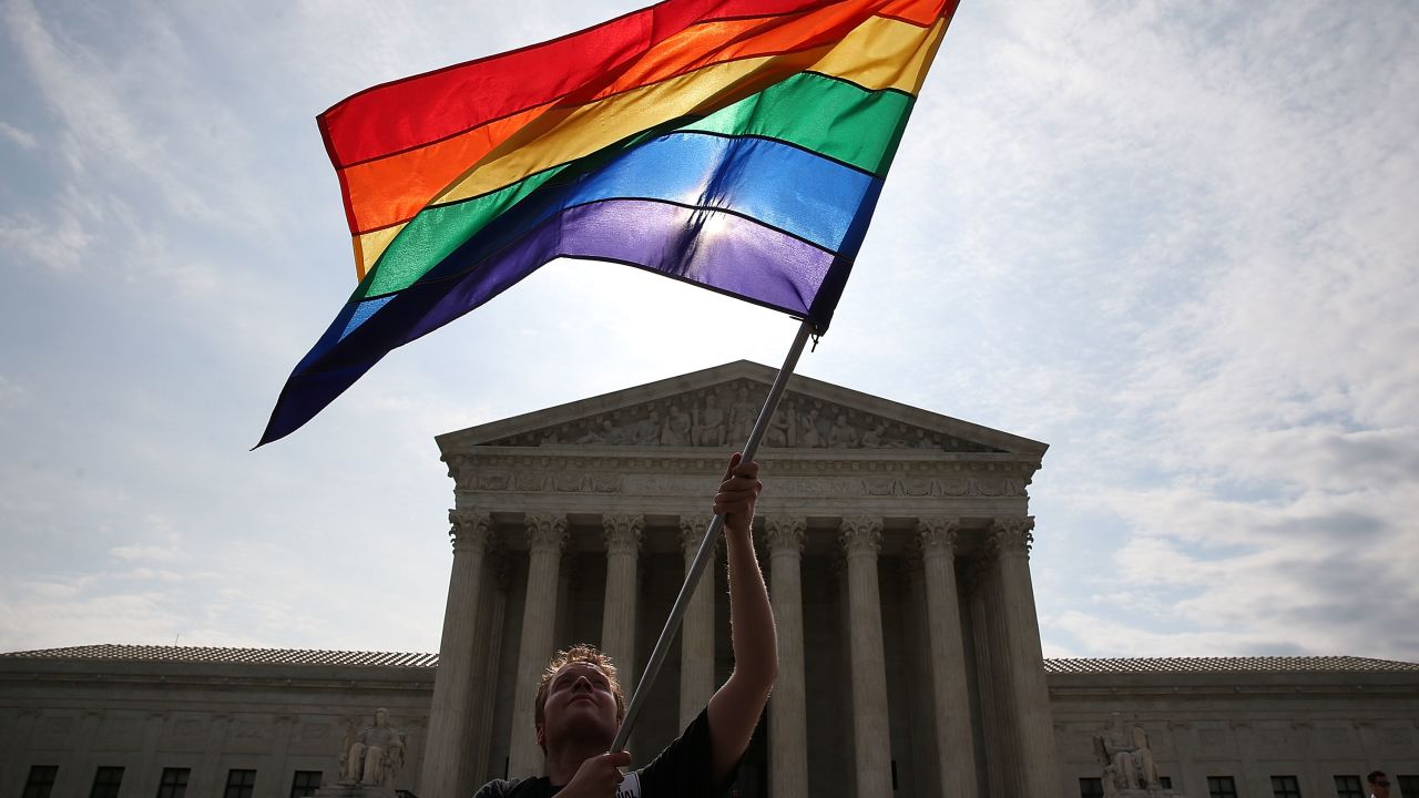 A rainbow flag is waved in front of the Supreme Court in Washington.
