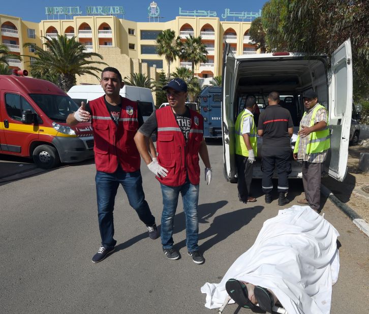 Tunisian medics stand near a tourist's body.