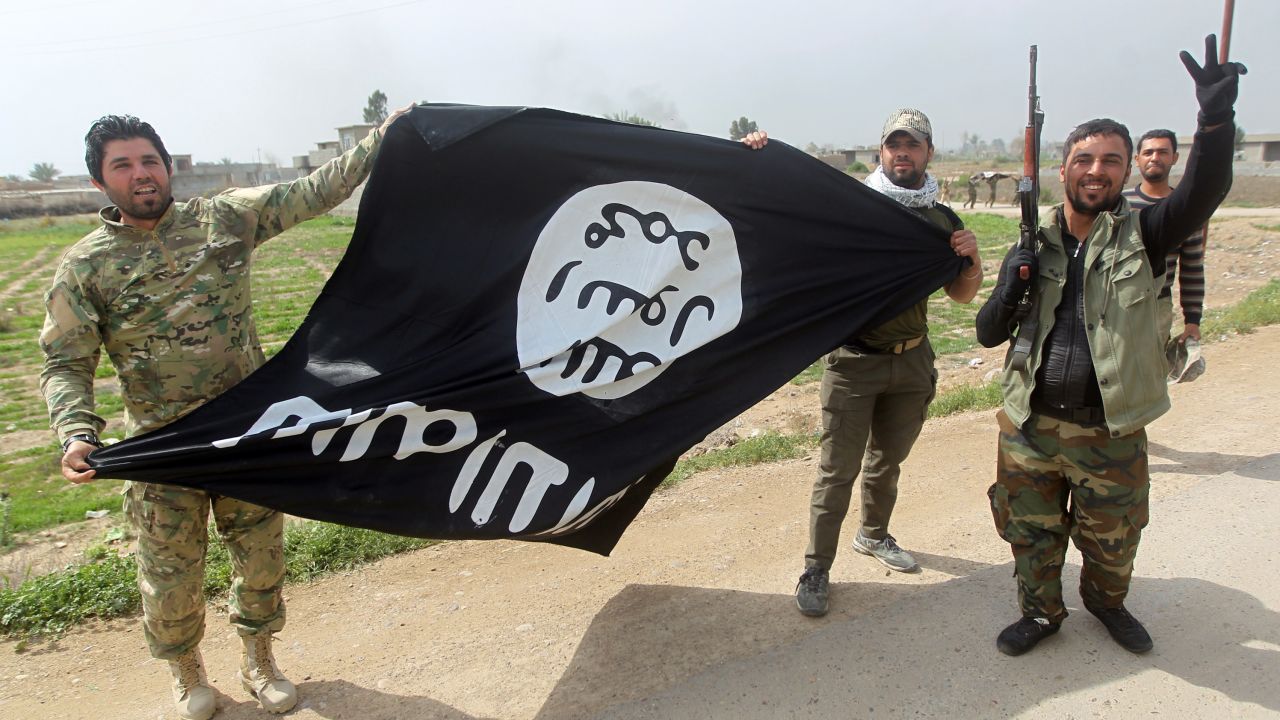 Members of Iraqi paramilitary Popular Mobilisation units, which are dominated by Shiite militias, celebrate with a flag of the Islamic State (IS) group after retaking the village of Albu Ajil, near the city of Tikrit, from the jihadist group, on March 9, 2015.