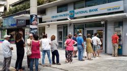 Greeks line up Sunday to withdraw cash at an ATM in Athens.