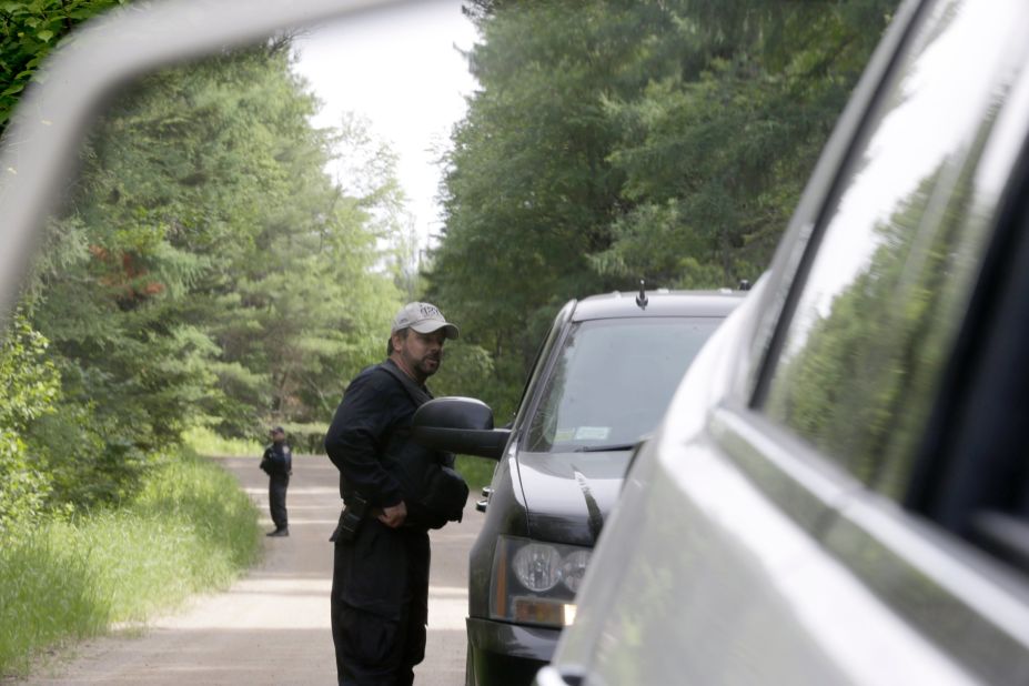 Law enforcement officials are seen in the side-view mirror of a car as they stand guard June 28 in Duane, New York.