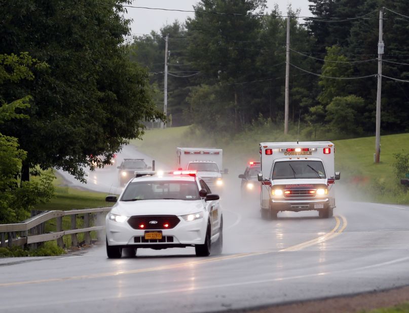 Police escort ambulances from an area where law enforcement officers were searching for Sweat on June 28.