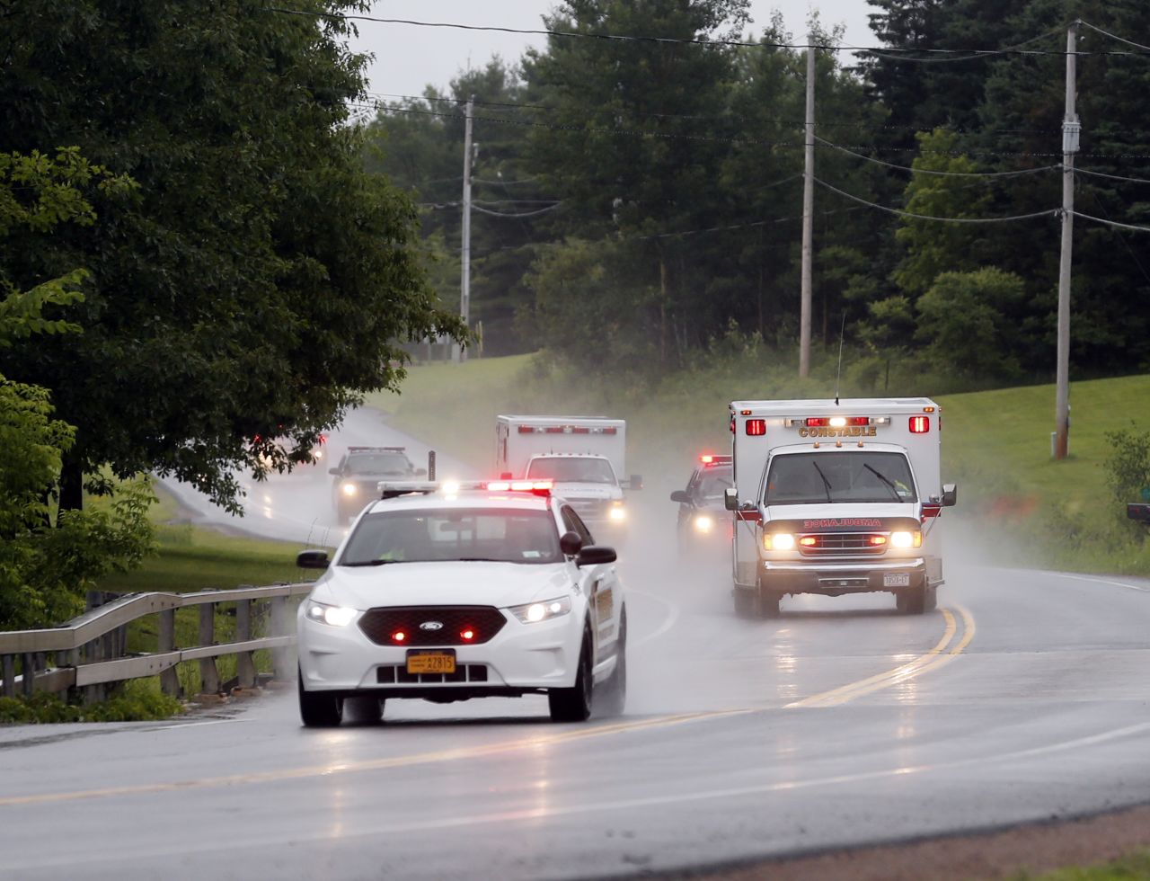 Police escort ambulances from an area where law enforcement officers were searching for Sweat on June 28.