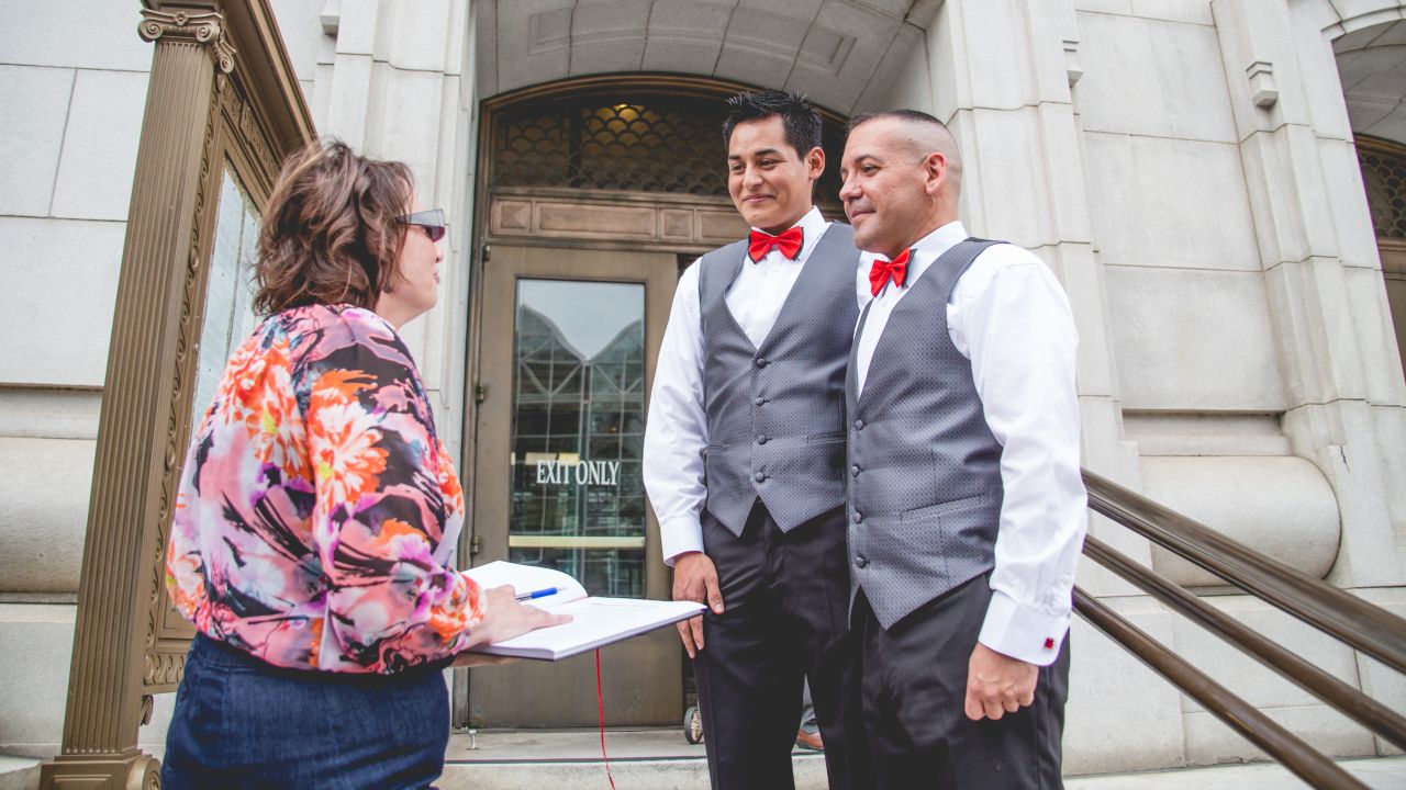 David Herrera-Santos, center, and Carlos Santos-Herrera, right, stand with wedding officiant Kimberley Boncella.