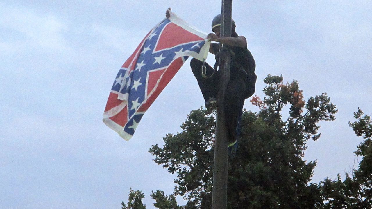 Bree Newsome of Charlotte, N.C., removes the Confederate battle flag at a Confederate monument at the Statehouse in Columbia, S.C., on Saturday, June, 27, 2015. She was taken into custody when she came down. The flag was raised again by capitol workers about 45 minutes later. (AP Photo/Bruce Smith)