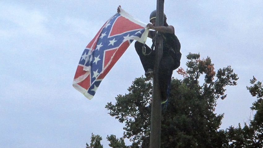 Bree Newsome of Charlotte, N.C., removes the Confederate battle flag at a Confederate monument at the Statehouse in Columbia, S.C., on Saturday, June, 27, 2015. She was taken into custody when she came down. The flag was raised again by capitol workers about 45 minutes later.  (AP Photo/Bruce Smith)