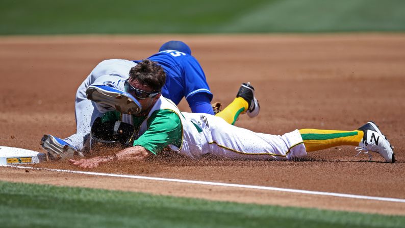 Oakland's Sam Fuld, bottom, slides safely into third base as Kansas City's Mike Moustakas tries to make the tag on Saturday, June 27.
