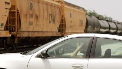 A driver waits for a freight train to pass a grade crossing on June 16, 2006, in Elmhurst, Illinois.