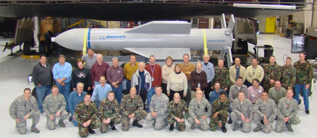 Weapon specialists gather in front of a mock up of the Massive Ordnance Penetrator and the B-2 weapons load trainer at Whitman Air Force Base, Missouri.