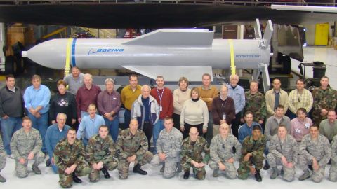 Weapon specialists gather in front of a mock up of the Massive Ordnance Penetrator and the B-2 weapons load trainer at Whitman Air Force Base, Missouri.