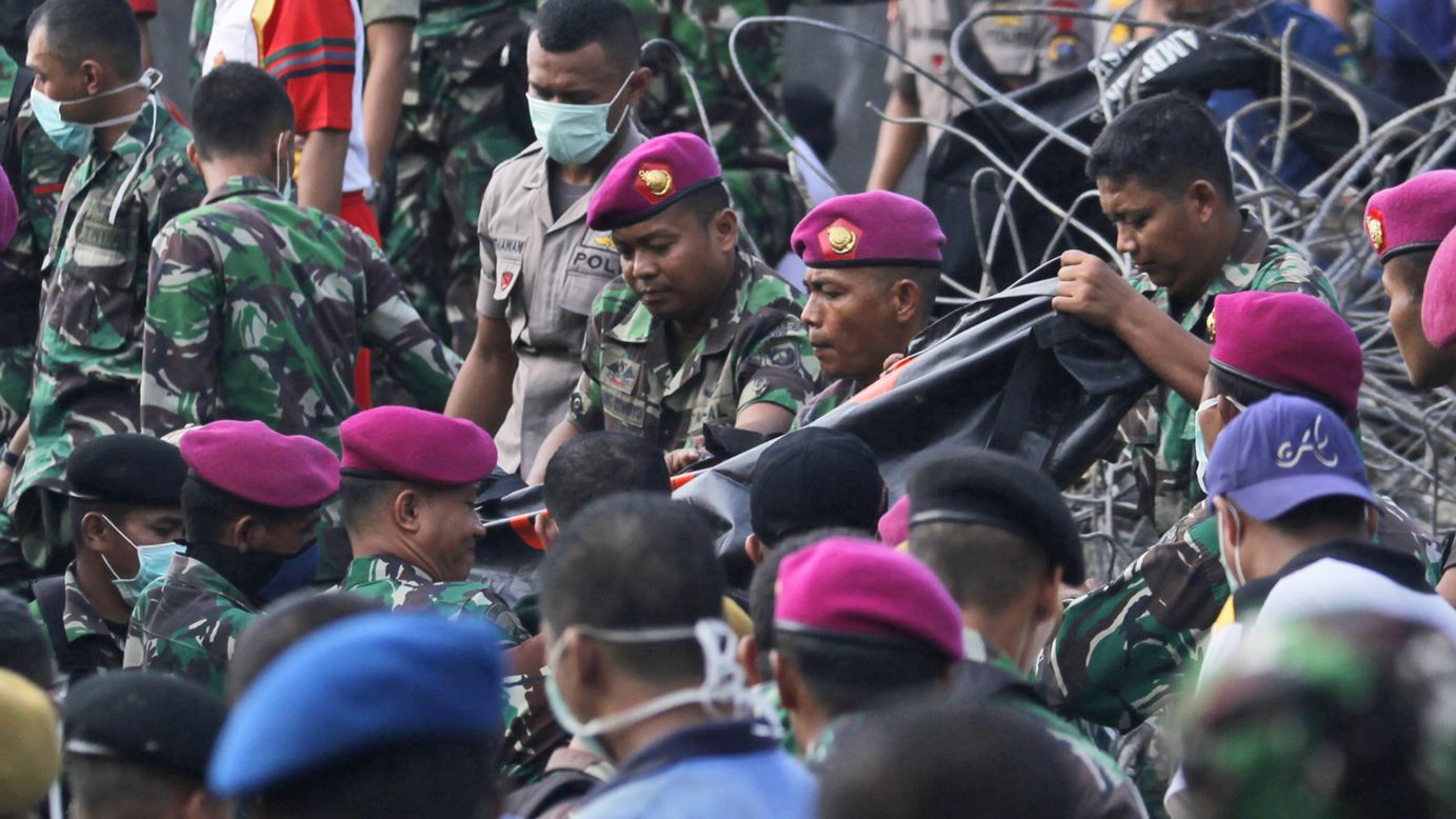 Indonesian military personnel carry the body of a victim away from the crash site.