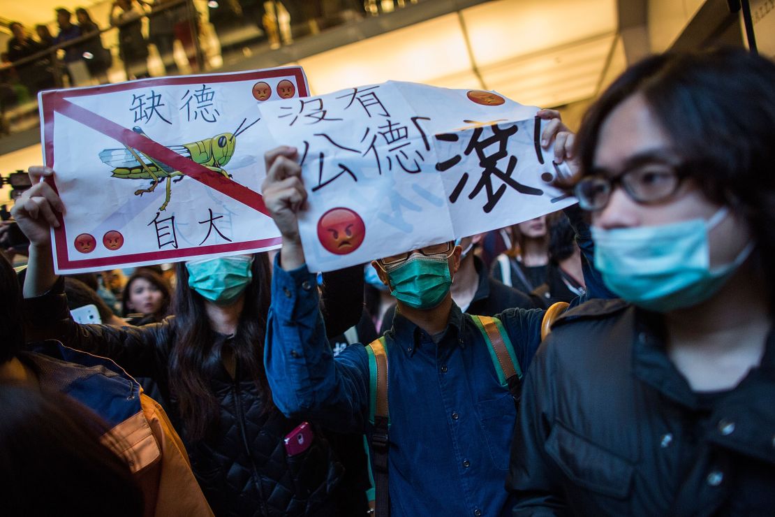 Protesters march to a shopping mall in Shatin, Hong Kong February 15, 2015. One protester holds a placard with a picutre of a locust. 