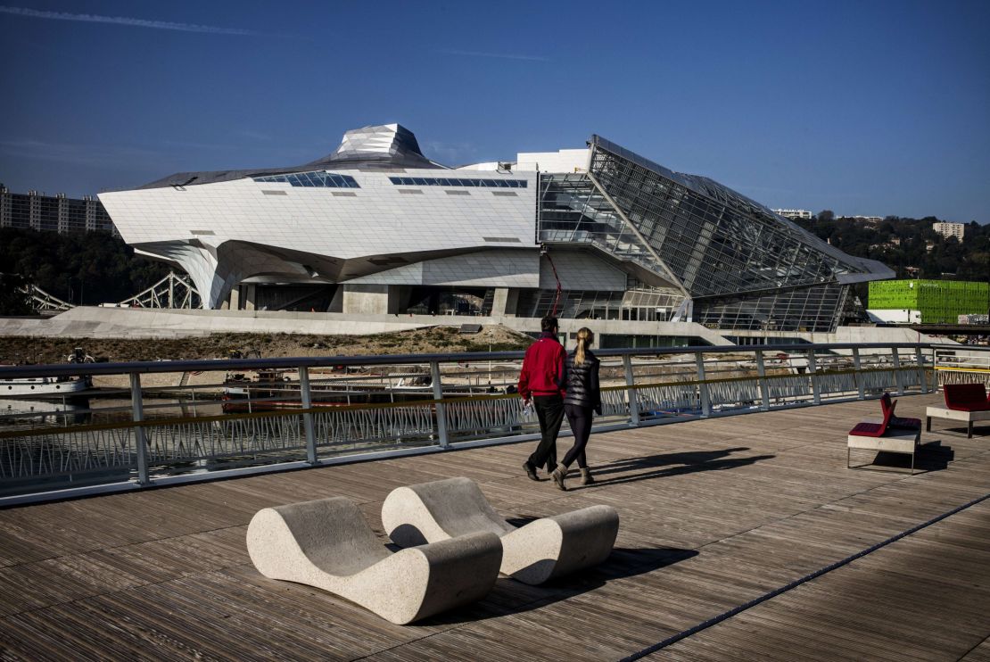 A couple walks past the Musee des Confluences science centre and anthropology museum in Lyon, France.