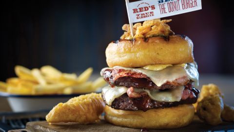 Red's True Barbecue's donut burger, found in the UK, allows you to eat lunch and dinner at the same time. Two beef patties, strips of bacon and cheese are sandwiched between two glazed donuts. 
