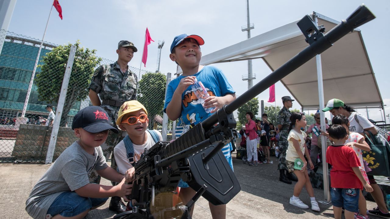 Soldiers watch as children play with machine guns -- not loaded, of course.