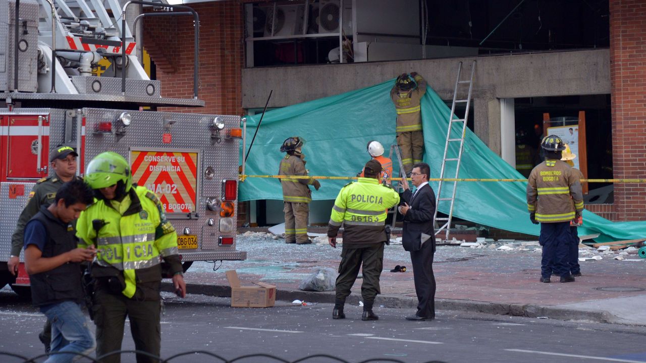 Colombian police officers and firefighters check the site of an explosion in the financial heart of Bogota.