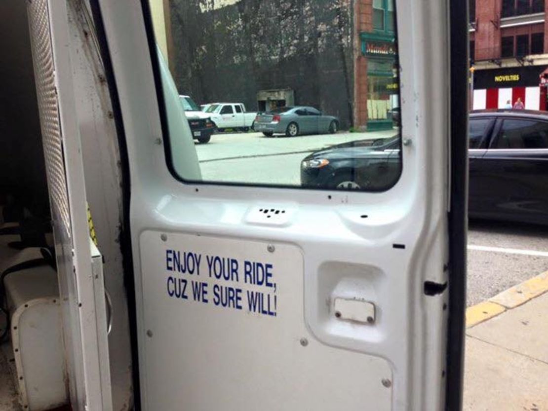 A sign inside the back door of a Baltimore police detainee transport vehicle warns about the ride