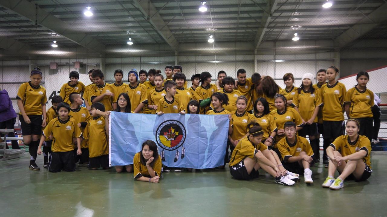 Team photo -- players from the communities of Fort Liard and Behchoko pose with the flag of Fort Liard at the Polar Cup.