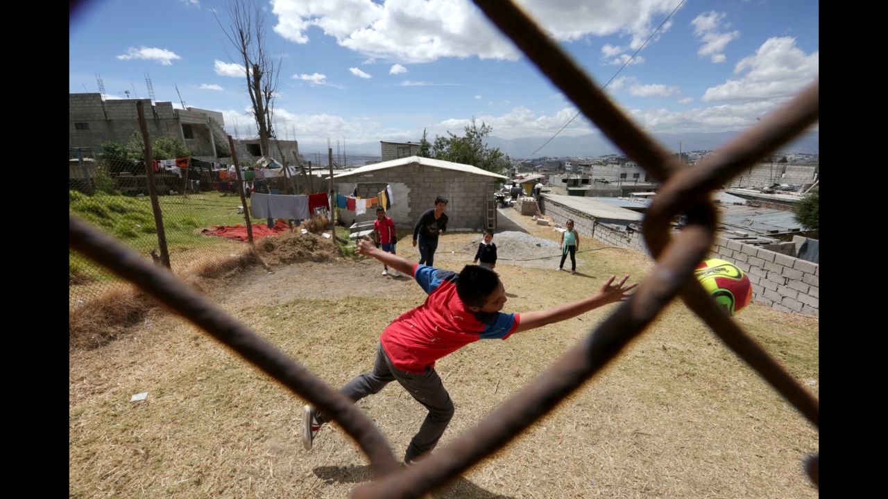 Steven Ordonez, 13, in the center back, hits the soccer ball past a goalie in a makeshift soccer game at his neighbor's house in North Quito. 