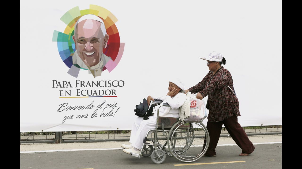 A woman is wheeled past a banner with an image of Pope Francis at Samanes Park on July 5. 
