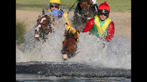 Horses race through a water obstacle during an equestrian event in Hamburg, Germany, on Tuesday, June 30.