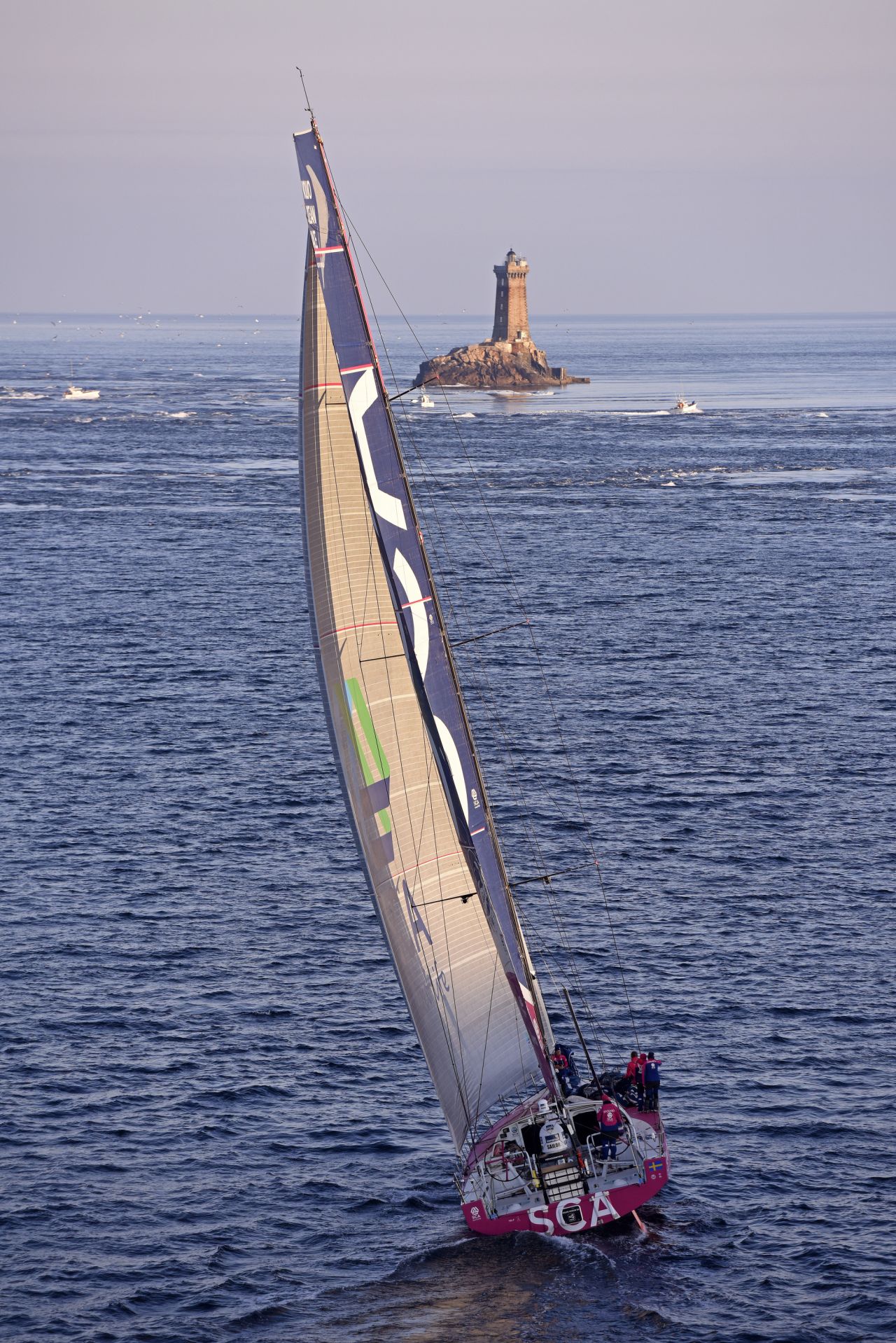 On a sparkling afternoon of sailing, the SCA boat navigates waters by an offshore lighthouse. Each crew in the race sailed an identically-designed boat.