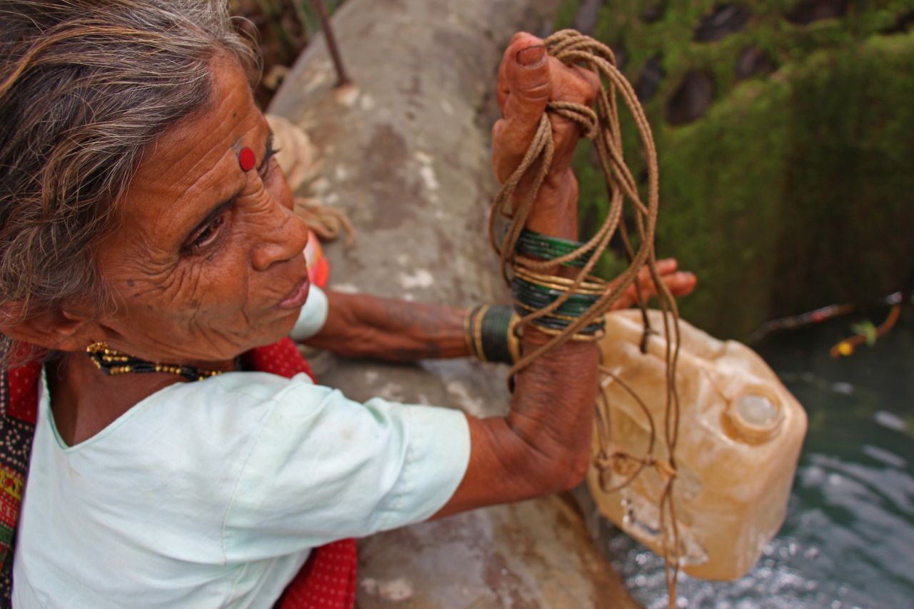 Sakhri, the second wife, pulls out a container filled with water from the well.