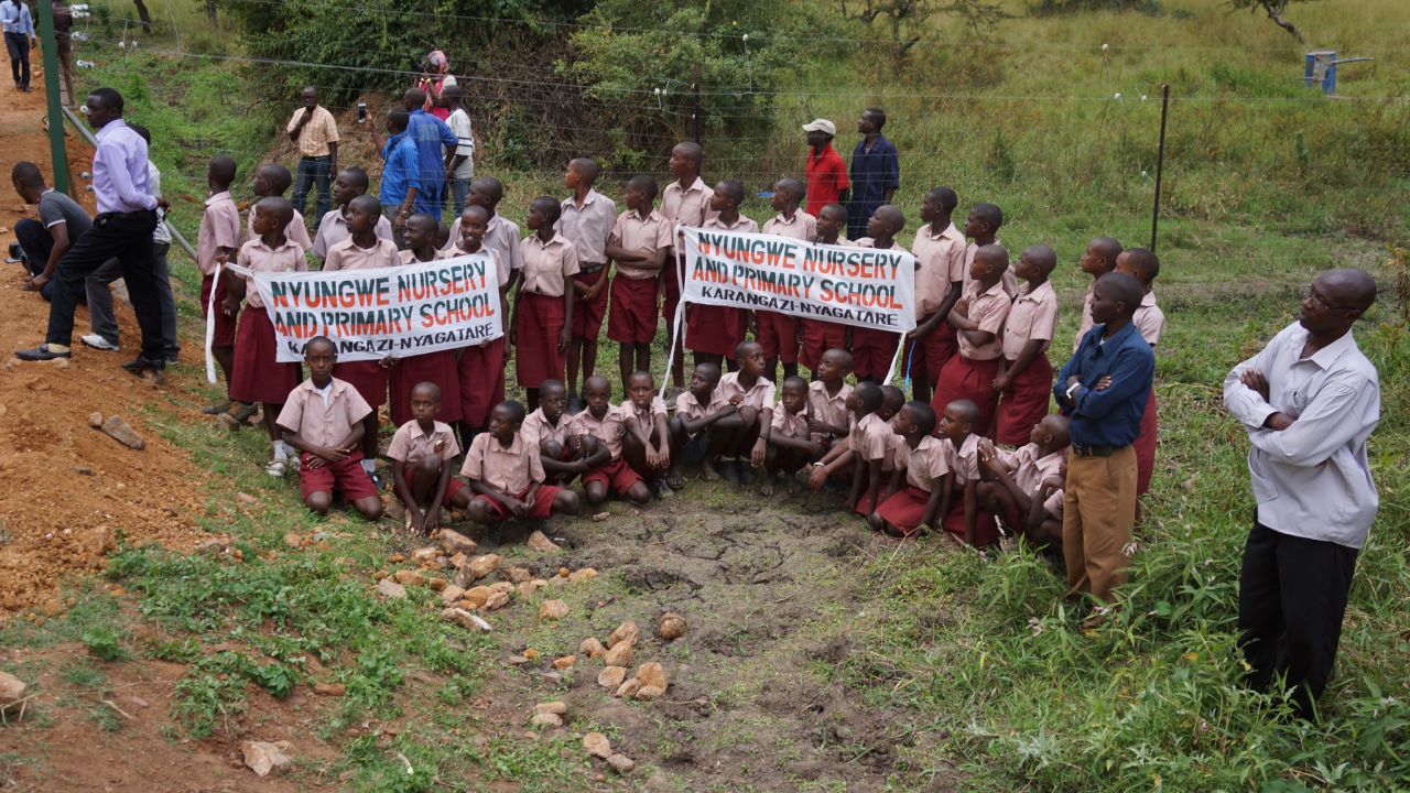 Rwandans, including schoolchildren, wait to welcome the arrival of the lions at Akagera National Park in Rwanda on June 30.