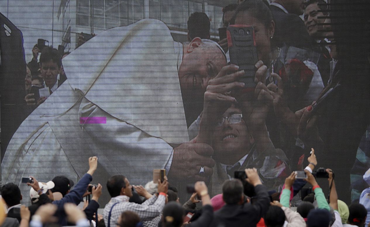 A crowd watches Francis on a video screen as he poses for a selfie during his visit to the Catholic University in Quito on July 7.