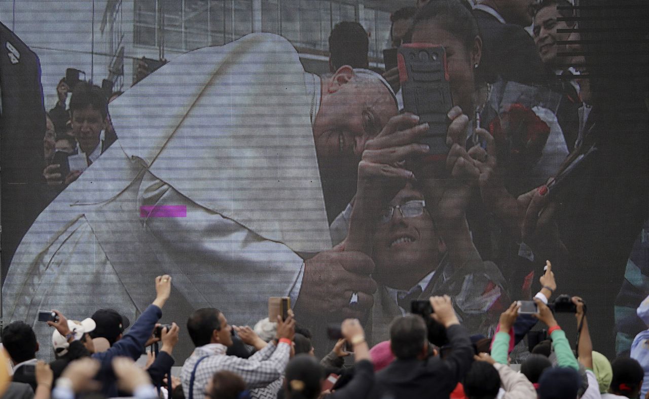 A crowd watches Francis on a video screen as he poses for a selfie during his visit to the Catholic University in Quito on July 7.