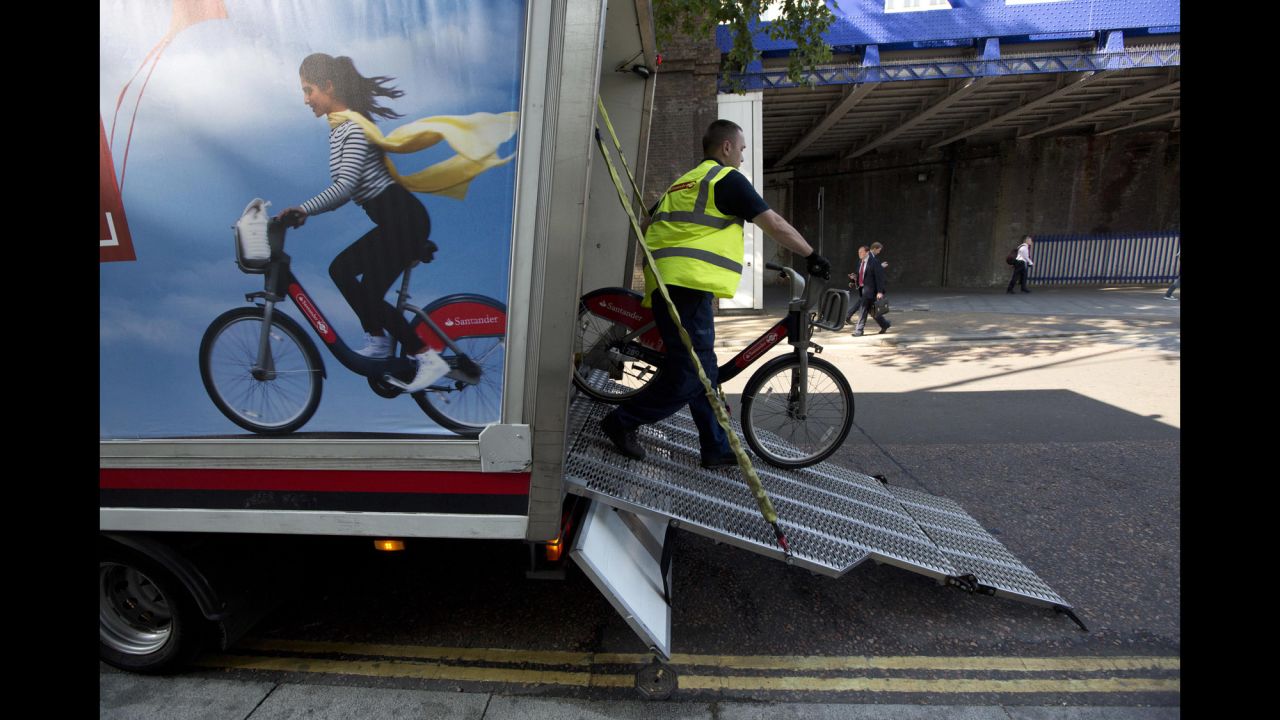 A man unloads bicycles to resupply a city bike-sharing station in London.